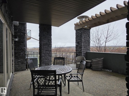 The property features an expansive outdoor patio with a textured floor and stone-clad pillars - 304 5201 Brougham Drive, Drayton Valley, AB - Outdoor With Exterior