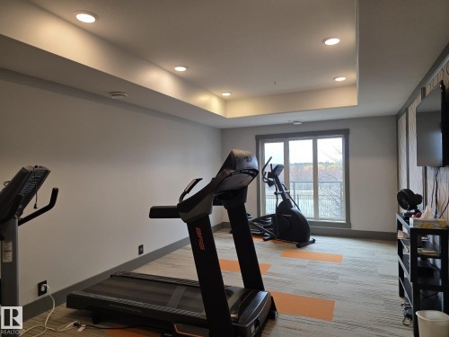 The property includes a fitness area with recessed lighting, a window providing natural light, and carpeted flooring - 304 5201 Brougham Drive, Drayton Valley, AB - Indoor Photo Showing Gym Room