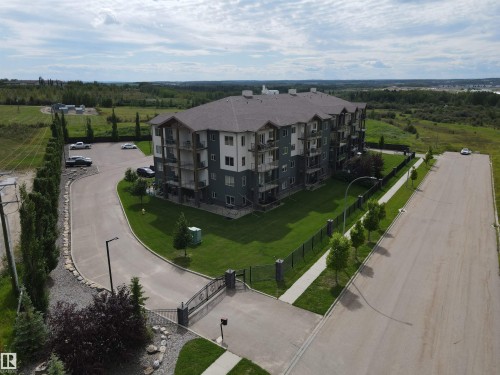 The property features a multi-story building with balconies, a paved parking area, and a well-maintained lawn - 304 5201 Brougham Drive, Drayton Valley, AB - Outdoor With View