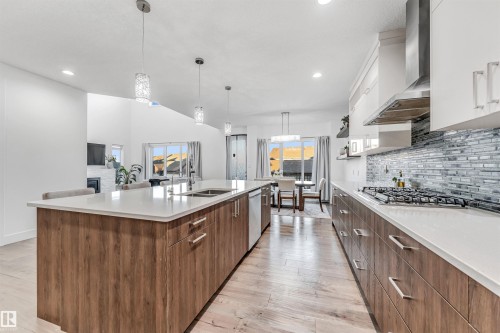 The kitchen features a large island with a sink, wood-look cabinetry, and white countertops - 1407 Graydon Hill Way, Edmonton, AB - Indoor Photo Showing Kitchen With Double Sink With Upgraded Kitchen