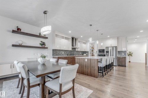 The dining area features a large table with seating for six, illuminated by a decorative pendant light - 1407 Graydon Hill Way, Edmonton, AB - Indoor Photo Showing Dining Room