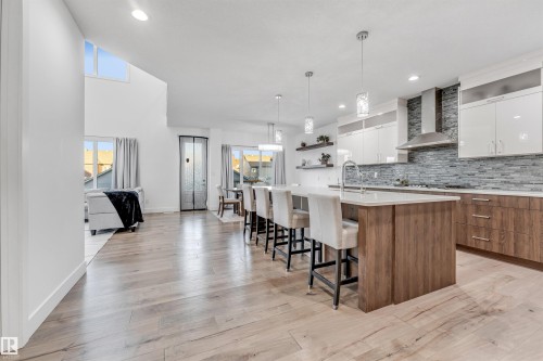 Contemporary open-concept living space featuring hardwood floors, a kitchen island with seating, pendant lighting, and a modern kitchen with a tiled backsplash - 1407 Graydon Hill Way, Edmonton, AB - Indoor Photo Showing Other Room