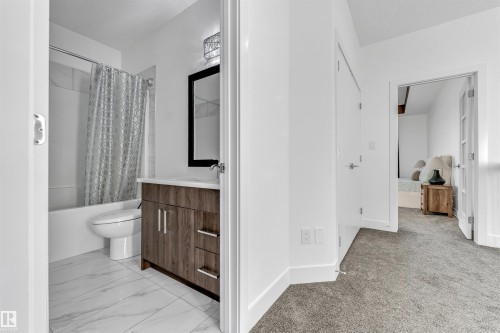 Bathroom featuring a modern vanity with integrated sink, a bathtub with shower, and tiled flooring - 1407 Graydon Hill Way, Edmonton, AB - Indoor Photo Showing Bathroom
