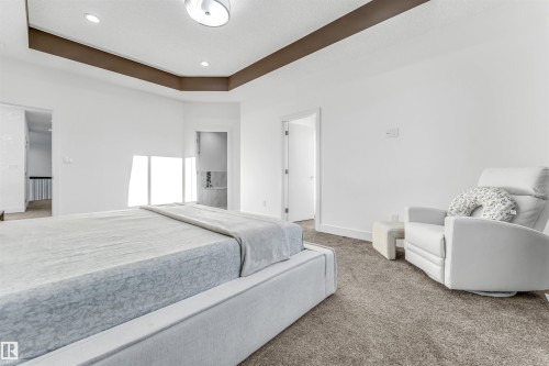 Spacious bedroom featuring clean white walls, a stylish tray ceiling with recessed lighting, and soft carpet flooring - 1407 Graydon Hill Way, Edmonton, AB - Indoor Photo Showing Bedroom