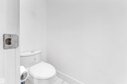 The powder room features a contemporary white toilet and light-colored floor tiling - 1407 Graydon Hill Way, Edmonton, AB - Indoor Photo Showing Bathroom