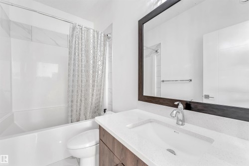 This bathroom features a vanity with a white countertop and an undermount sink, complemented by a large mirror with a dark frame - 1407 Graydon Hill Way, Edmonton, AB - Indoor Photo Showing Bathroom