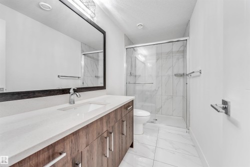 Bathroom featuring a wood-look vanity with a light-colored countertop, an undermount sink, and a large mirror - 1407 Graydon Hill Way, Edmonton, AB - Indoor Photo Showing Bathroom