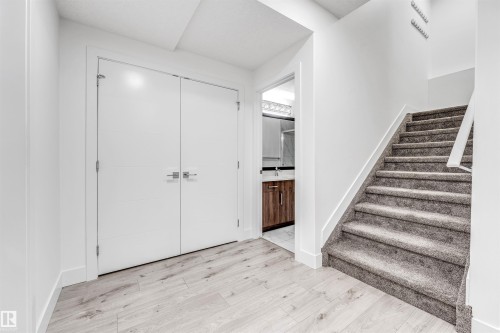 Entryway featuring light wood-look flooring, a white bi-fold door, and a carpeted staircase with a white railing - 1407 Graydon Hill Way, Edmonton, AB - Indoor Photo Showing Other Room