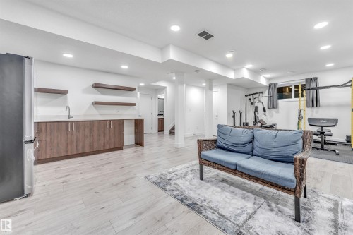 This versatile space features light-toned flooring, recessed lighting, and a built-in wet bar with a sink and floating shelves - 1407 Graydon Hill Way, Edmonton, AB - Indoor Photo Showing Other Room