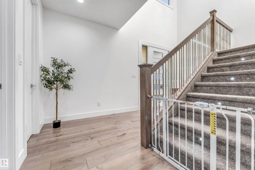 Entryway featuring light-colored hardwood flooring, white walls, and a staircase with carpeted treads and a wooden railing - 1407 Graydon Hill Way, Edmonton, AB - Indoor Photo Showing Other Room