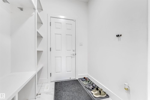 Entryway featuring white built-in shelving, white paneled door, and white tile flooring - 1407 Graydon Hill Way, Edmonton, AB - Indoor