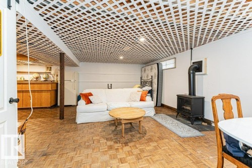 Rec Room area featuring parquet wood flooring, a white lattice ceiling, and a freestanding gas stove - 8 Duke Drive, Lamont, AB - 