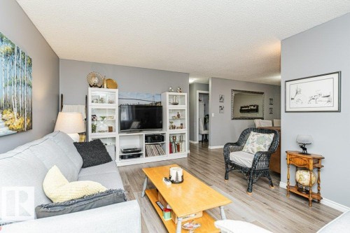 The living area features light-toned flooring, a light gray wall color, and a woven armchair with a light cushion - 8 Duke Drive, Lamont, AB - Indoor Photo Showing Living Room