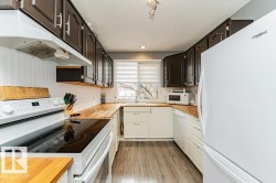 This kitchen features dark upper cabinetry, light lower cabinetry, and light wood countertops - 
