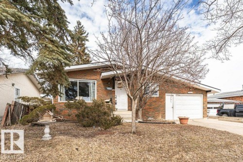 The property features a brick exterior, a driveway, and an attached garage with a white garage door - 8 Duke Drive, Lamont, AB - Outdoor