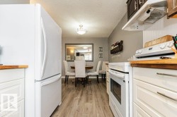 The kitchen features white cabinetry with wood countertops, a white refrigerator, and a white oven - 