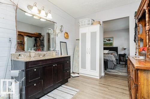 Bathroom featuring a vanity with a granite countertop, a large mirror with a decorative frame, and a wall-mounted light fixture - 8 Duke Drive, Lamont, AB - Indoor Photo Showing Bathroom
