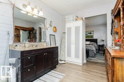 Bathroom featuring a vanity with a granite countertop, a large mirror with a decorative frame, and a wall-mounted light fixture - 