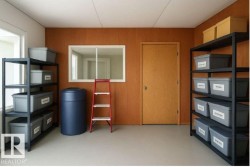 Spacious storage area featuring light-colored flooring, a window, and a wooden door - 