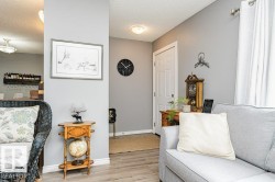 Living area featuring light grey walls, light-colored flooring, and a white entrance door - 