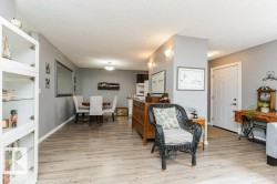 The property features light-colored flooring throughout, a dining area with a round table and upholstered chairs, and a front entry door with paneling - 