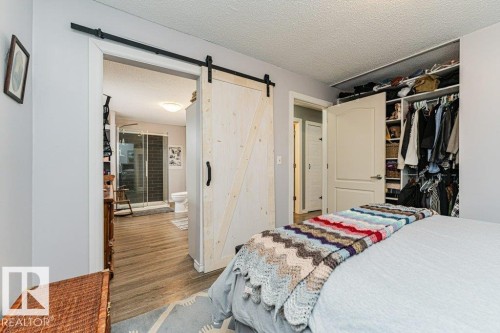 The property features a bedroom with a sliding barn door leading to a bathroom, and a built-in closet with shelving and hanging space - 8 Duke Drive, Lamont, AB - Indoor Photo Showing Bedroom
