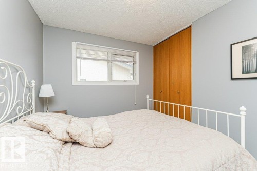 This room features a window with blinds, light blue walls, and a wood-toned closet with double doors - 8 Duke Drive, Lamont, AB - Indoor Photo Showing Bedroom