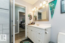 The bathroom features a white vanity with a white countertop and a framed mirror - 