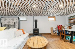 Living area with white walls, a visible floor grate, and a wood stove - 