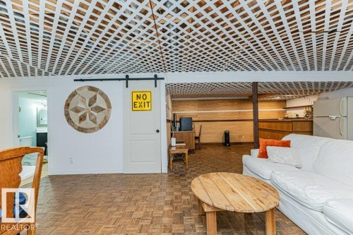 Spacious living area featuring a white lattice ceiling, wood parquet flooring, and a white sliding barn door - 8 Duke Drive, Lamont, AB - Indoor