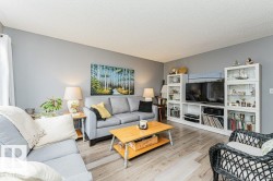 Living area featuring light gray walls, wood-look flooring, and a built-in media console with display shelving - 