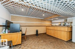 Recreation room featuring a patterned ceiling, wood paneling, and a built-in wooden counter - 