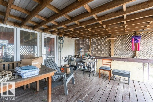 This property features a covered porch with exposed wooden beams and a metal roof - 8 Duke Drive, Lamont, AB -  With Deck Patio Veranda With Exterior