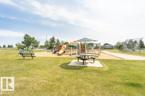 Neighborhood park area featuring a playground with slides, swings, and climbing structures, along with picnic tables and benches - 8 Duke Drive, Lamont, AB - Outdoor