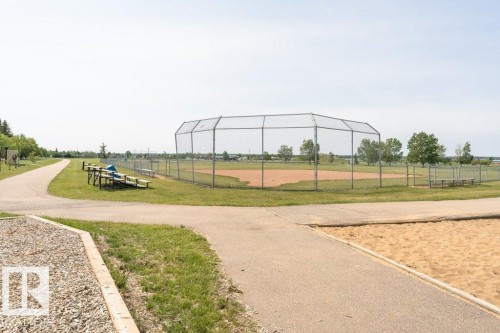 Community amenities include a baseball diamond with a chain-link fence, surrounded by green grass and paved pathways - 8 Duke Drive, Lamont, AB - Outdoor With View