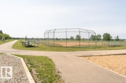 Community amenities include a baseball diamond with a chain-link fence, surrounded by green grass and paved pathways - 