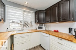 The kitchen features dark wood upper cabinetry, white lower cabinetry, and light wood countertops - 