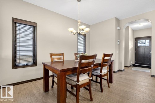 Dining area featuring light-toned flooring, a light fixture with multiple bulbs, and windows with blinds - 1530 Chapman Way, Edmonton, AB - Indoor Photo Showing Dining Room