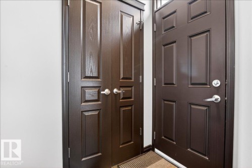 The property features a dark wood paneled door with a brushed nickel handle and lock, beside a similar style closet door with brushed nickel handles - 1530 Chapman Way, Edmonton, AB - Indoor Photo Showing Other Room