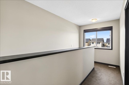 The property features a neutral color palette, carpeted flooring, and a window with views of surrounding properties - 1530 Chapman Way, Edmonton, AB - Indoor Photo Showing Other Room