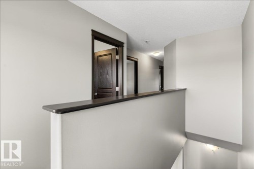 The property features a hallway with light gray walls, dark wood trim, and doors - 1530 Chapman Way, Edmonton, AB - Indoor Photo Showing Other Room