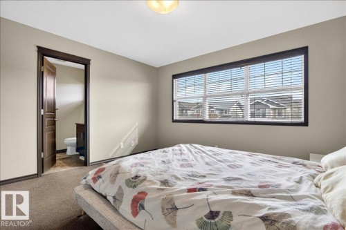 The property features a bedroom with a window offering views of the surrounding neighborhood, equipped with horizontal blinds for privacy - 1530 Chapman Way, Edmonton, AB - Indoor Photo Showing Bedroom