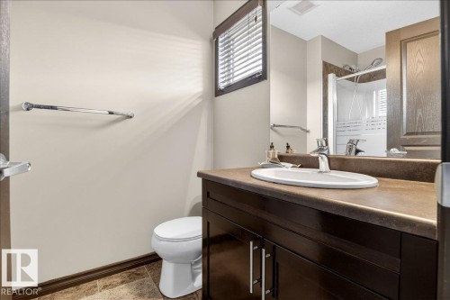 Well-appointed bathroom featuring a dark wood vanity with a solid surface countertop, a white oval sink with a chrome faucet, and a shower with a glass enclosure - 1530 Chapman Way, Edmonton, AB - Indoor Photo Showing Bathroom