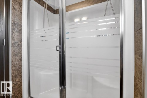 The bathroom features a shower with frosted glass doors, a white shower base, and light fixtures visible above the shower - 1530 Chapman Way, Edmonton, AB - Indoor Photo Showing Bathroom