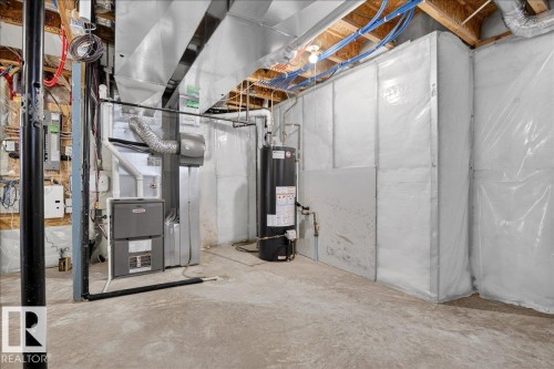 The property features a utility area with a furnace, water heater, and exposed ceiling joists - 1530 Chapman Way, Edmonton, AB - Indoor Photo Showing Basement