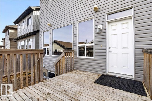 This property features a wooden deck with a matching wooden railing, leading to an exterior door with a transom window - 1530 Chapman Way, Edmonton, AB - Outdoor With Deck Patio Veranda With Exterior