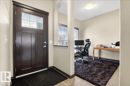 Inviting entryway with a dark wood door featuring a window panel, leading into a room with light-colored walls and a window with blinds - 1530 Chapman Way, Edmonton, AB - Indoor