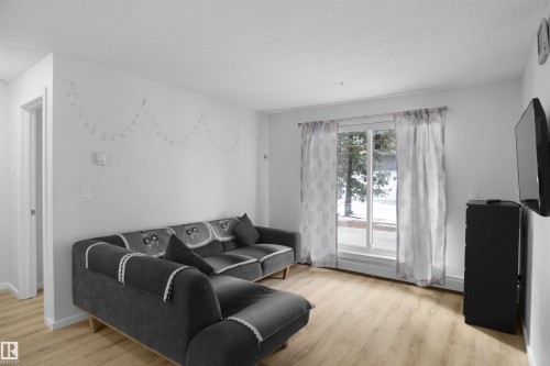 This living area features light-toned flooring and a window with a view of the outdoors - 103 3353 16A Avenue, Edmonton, AB - Indoor