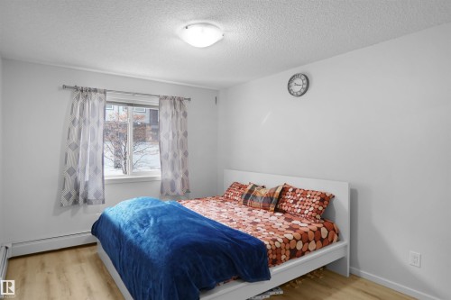 This bright room features light-toned flooring, a window with patterned drapes, and a ceiling light fixture - 103 3353 16A Avenue, Edmonton, AB - Indoor Photo Showing Bedroom