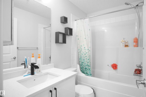 Bathroom featuring a white vanity with a rectangular sink, a black faucet, and a large mirror - 103 3353 16A Avenue, Edmonton, AB - Indoor Photo Showing Bathroom